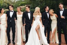 a group of people standing next to each other wearing formal wear and tuxedos