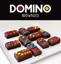 chocolate brownies with colorful candies are on a white plate and the words domino above them