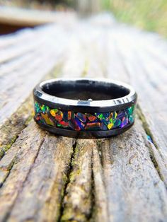 a black ring with colorful designs on it sitting on a wooden table next to grass