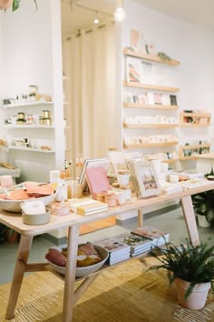 a table with books and other items on it in a room filled with potted plants