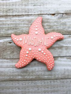 a pink starfish cookie with the word madison on it's side sitting on a wooden surface