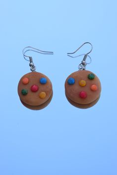 a pair of earrings with multicolored candy donuts hanging from hooks on a blue background