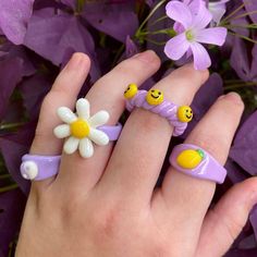 two rings with smiley faces on them are sitting in front of purple and white flowers