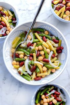 two bowls filled with beans, onions and green beans on top of a marble table