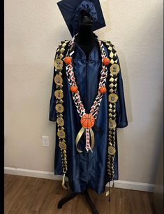 a blue graduation gown and cap with basketball decorations on it, sitting on a stand in front of a white wall