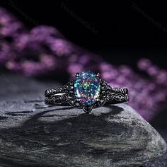 a ring with an opal colored stone in the center on top of a rock