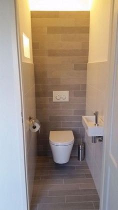 a white toilet sitting inside of a bathroom next to a wall mounted faucet