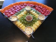 a platter filled with fruit and dips on top of a table