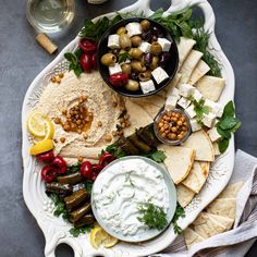 a platter with hummus, olives, pita bread and other foods