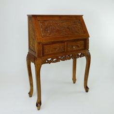 an antique wooden desk with drawers and carvings on the top, against a white background