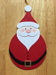 a paper santa claus ornament hanging on a wooden table