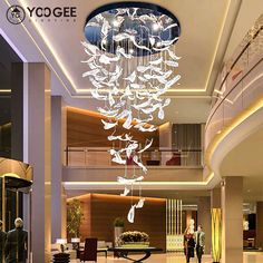 a large chandelier hanging from the ceiling in a lobby with people walking by