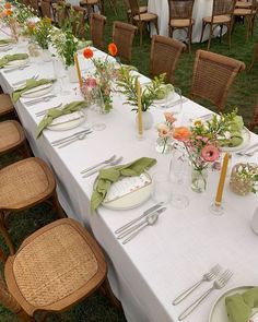 a long table set with place settings and flowers