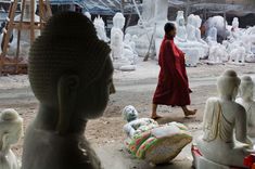 a woman walking past statues in an outdoor area that looks like it has been made out of clay