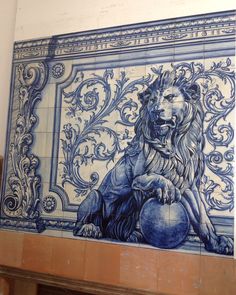 a blue and white tile wall with a lion holding a ball in it's paws