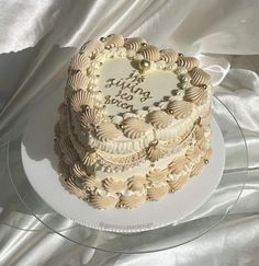 a heart shaped cake on a plate with white fabric in the background and a silver ribbon around it