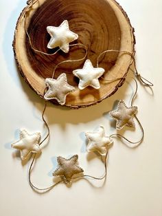 small white stars are hanging from string on a wood slice