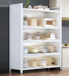 a white shelf filled with lots of items on top of a hard wood floor next to a kitchen counter