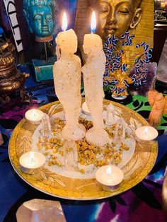 two candles are lit on a plate with flowers and other decorations in the back ground