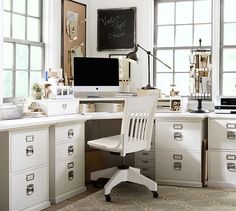 a white desk with a computer on top of it in front of two large windows