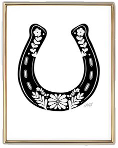 a black and white drawing of a horse shoe with flowers on the side, in a gold frame