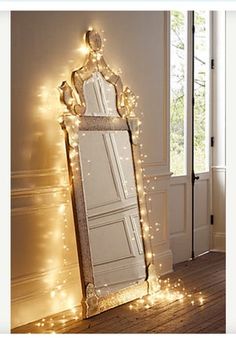 a large mirror sitting on top of a wooden floor next to a wall covered in lights