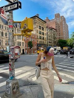 a woman walking across a street next to a traffic light