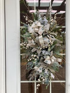 a christmas wreath on the front door of a house decorated with silver and white ornaments