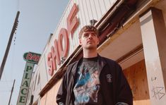 a man standing in front of a store with his hands in his pockets and looking up at the sky