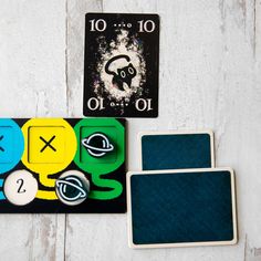 two matching coasters and one playing card on a white wooden background with space symbols