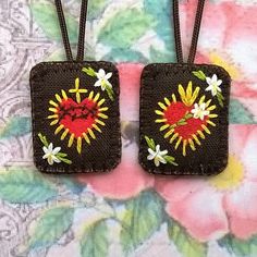 two small square shaped bags with flowers on them are hanging from a flowery background