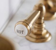 a close up of a brass faucet with the word hot written on it