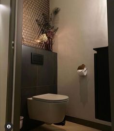 a bathroom with a white toilet sitting next to a wall mounted paper dispenser