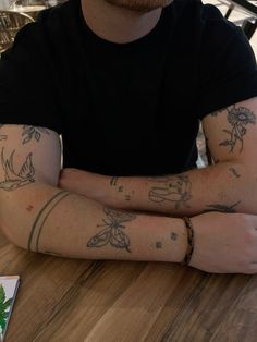 a man sitting at a table with his arms crossed and tattoos on his arm,