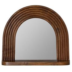 a wooden arch mirror sitting on top of a shelf