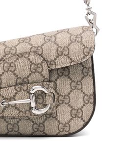 Find GUCCI 1955 Horsebit Shoulder Bag on Editorialist. The Gucci 1955 Horsebit Shoulder Bag is crafted from GG Supreme canvas with calf leather details. This mini shoulder bag features a Horsebit detail, a detachable shoulder strap, a detachable chain-link shoulder strap, a flap closure, and a main compartment with a logo patch. The bag has a canvas lining and silver-tone hardware. It is an asymmetrical design with a flap open closure and a turn lock. The bag can be worn on the shoulder or crossbody. Gucci Mini, Gucci Women, Gucci Horsebit, Type One, Bottega Veneta Shoulder Bag, Mini Shoulder Bag, Asymmetrical Design, Design Silver, Beige Brown