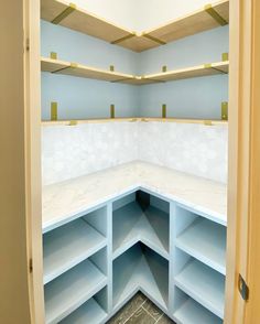 an empty room with blue shelves and white counter tops in the corner, as seen from the doorway