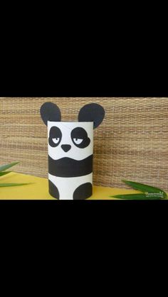 a toilet paper roll with a black and white panda face on it sitting next to some plants