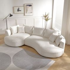 a living room with a large white sectional couch and rugs on the wooden floor