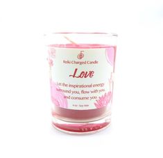 a pink candle that is sitting on a white surface with the words love written in it