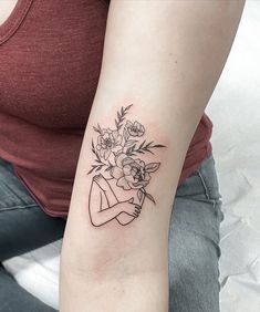 a woman with a tattoo on her arm holding a bouquet of flowers in her hand