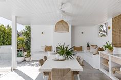 an outdoor dining area with wicker furniture and potted plants on the side wall