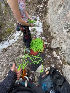 two people standing next to each other on top of a snow covered slope with green cords