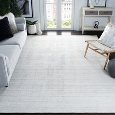 a living room with a white rug and black accents on the floor, couches and chairs