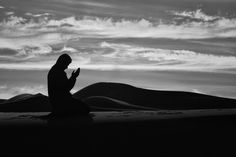 a person kneeling down in the desert praying