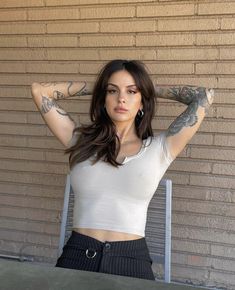 a woman with tattoos on her arms posing for the camera