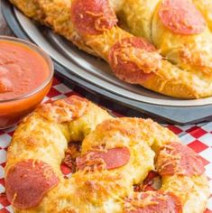 two plates with pizza rings and a bowl of tomato sauce