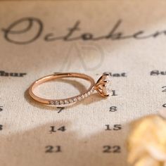 a diamond ring sitting on top of a piece of paper next to a yellow flower