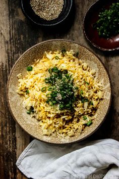 a bowl filled with rice and greens on top of a wooden table