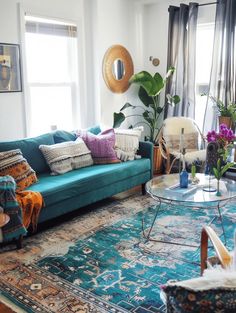 a living room filled with furniture and lots of plants on top of a blue rug